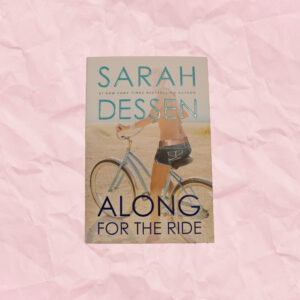 Book cover with girl in a bathing suit top and shorts riding a blue bike on the beach