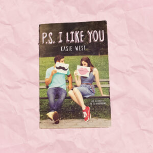 A book cover with a boy and girl sitting on a bench holding up cards that have a mustache and lips
